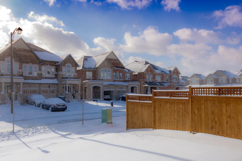 Suburban houses with snow-covered roofs under a clear winter sky.