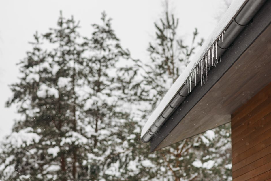 Icicles hanging from the snow-covered edge of a roof.