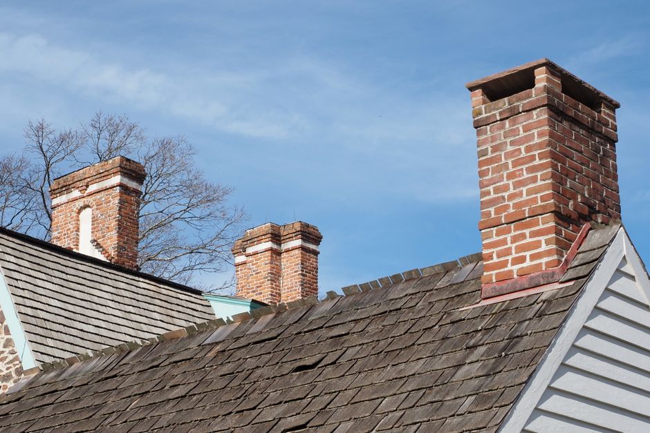 Brick chimneys rising from a residential rooftop under a clear sky.